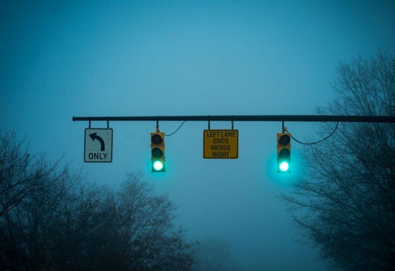 Two green traffic lights on a misty evening